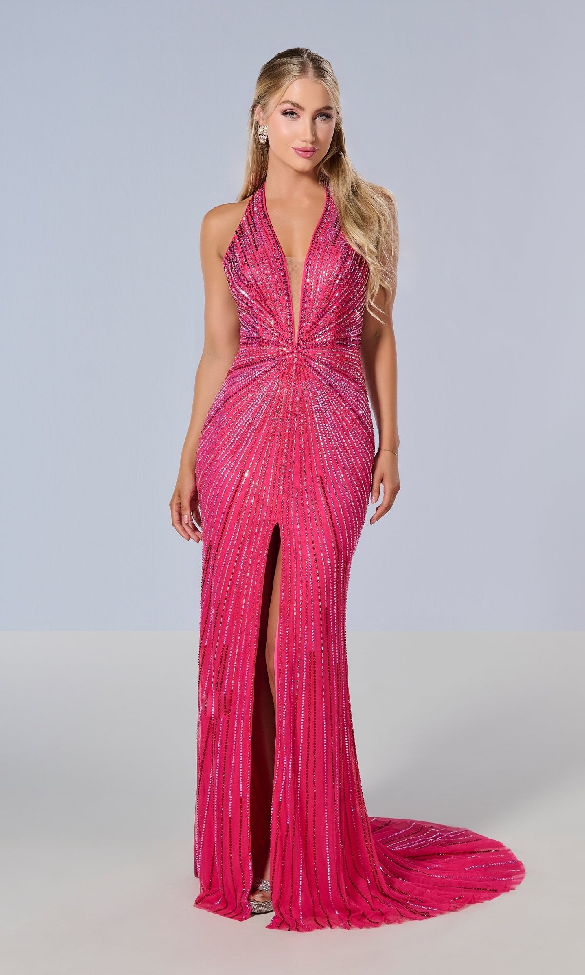 A woman wears the Tiffany 16205 Long Prom Dress, a bright pink floor-length halter gown with sparkling embellishments, plunging neckline, beaded prom design, and front slit against a plain light background.